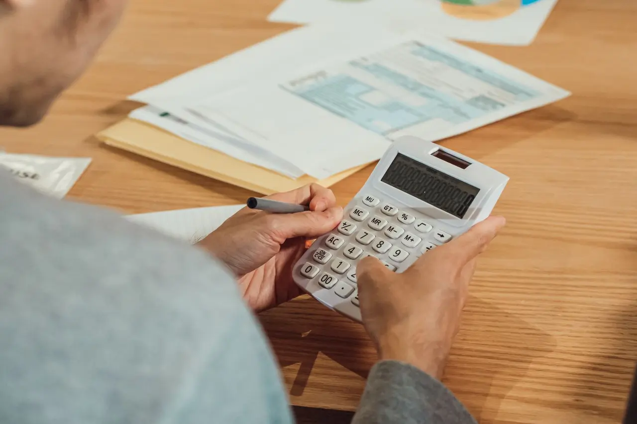 Person reviewing financial documents with a calculator at a desk