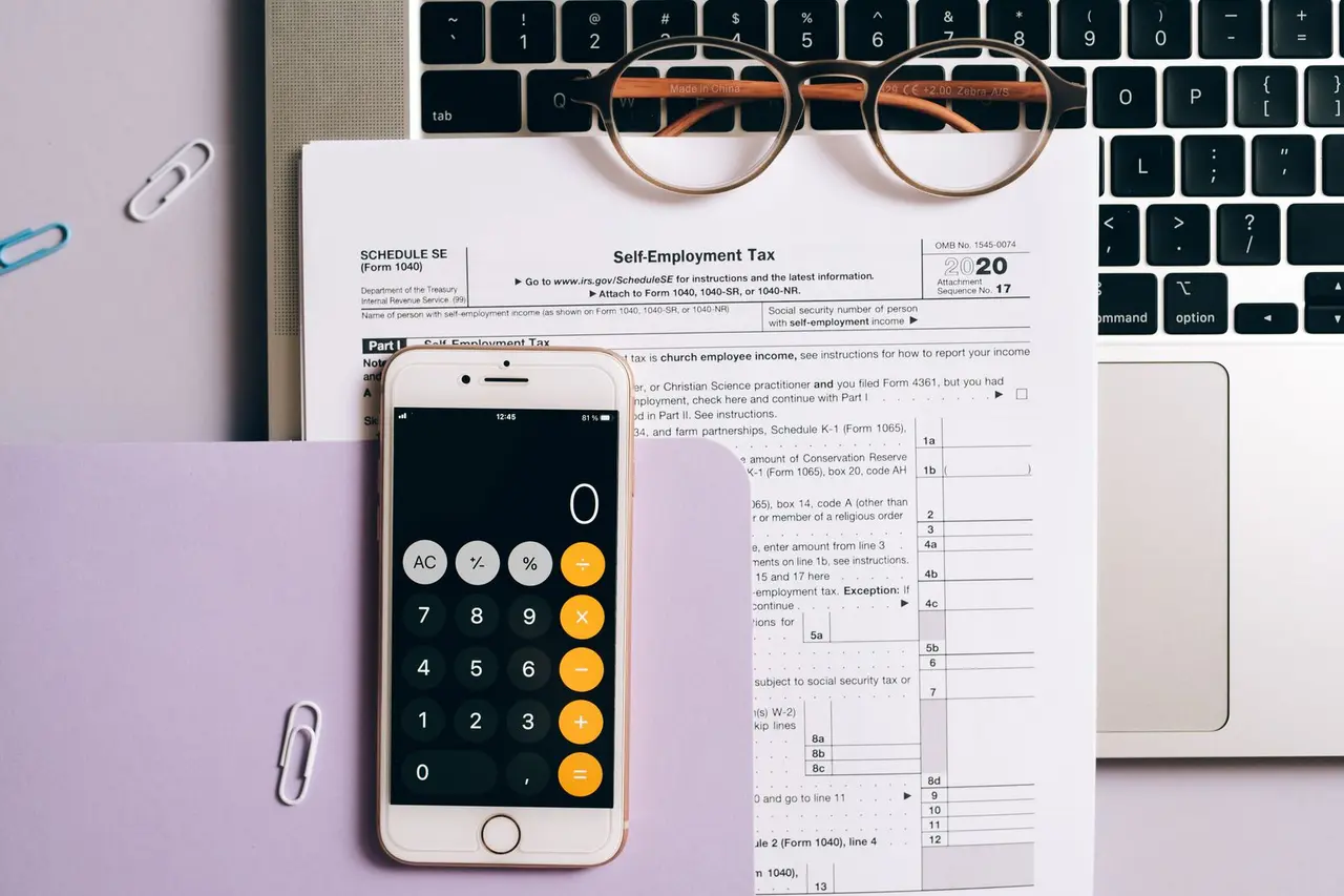 Phone calculator and laptop used to review business software costs