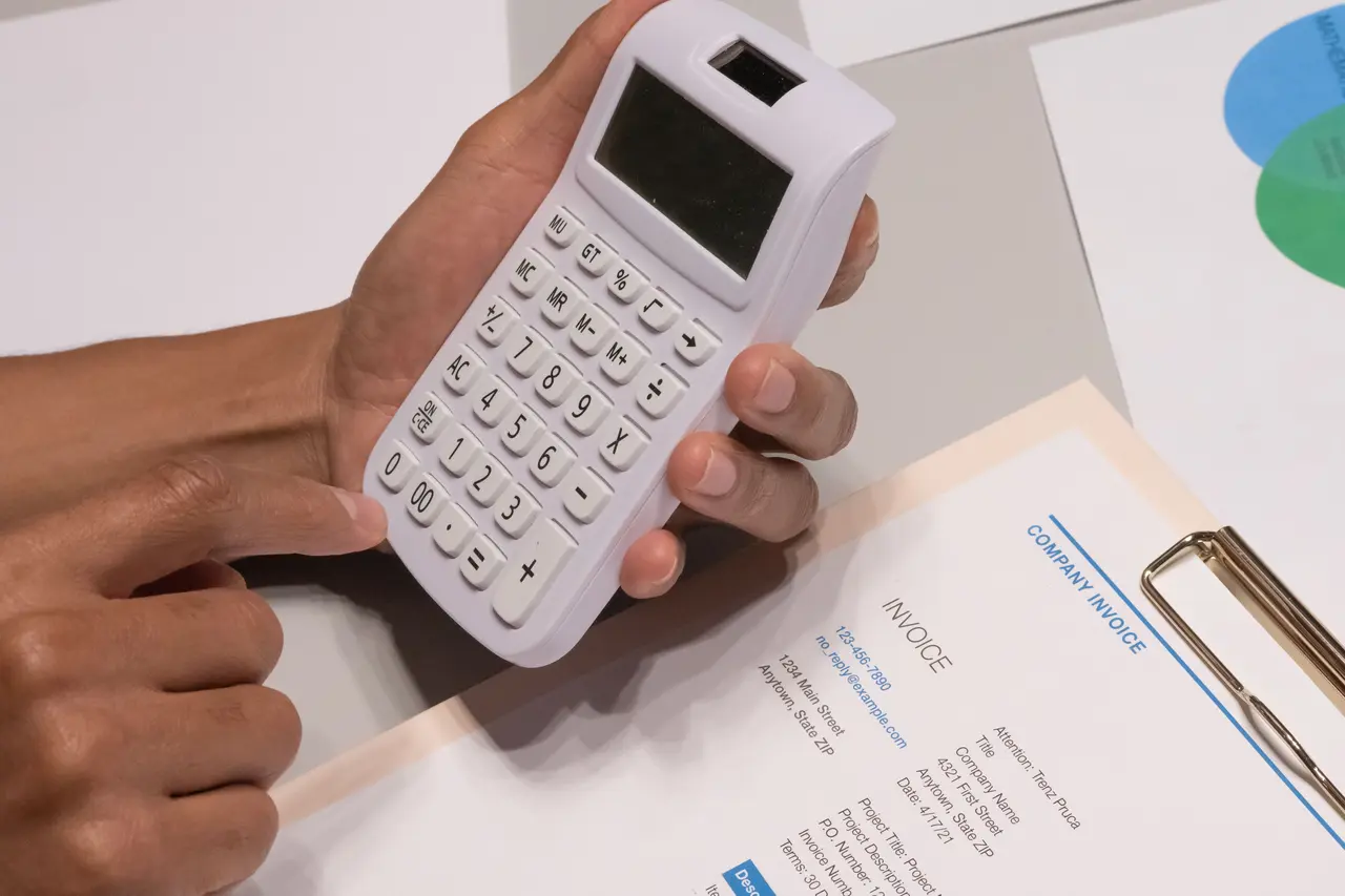 Person calculating an invoice with a handheld calculator