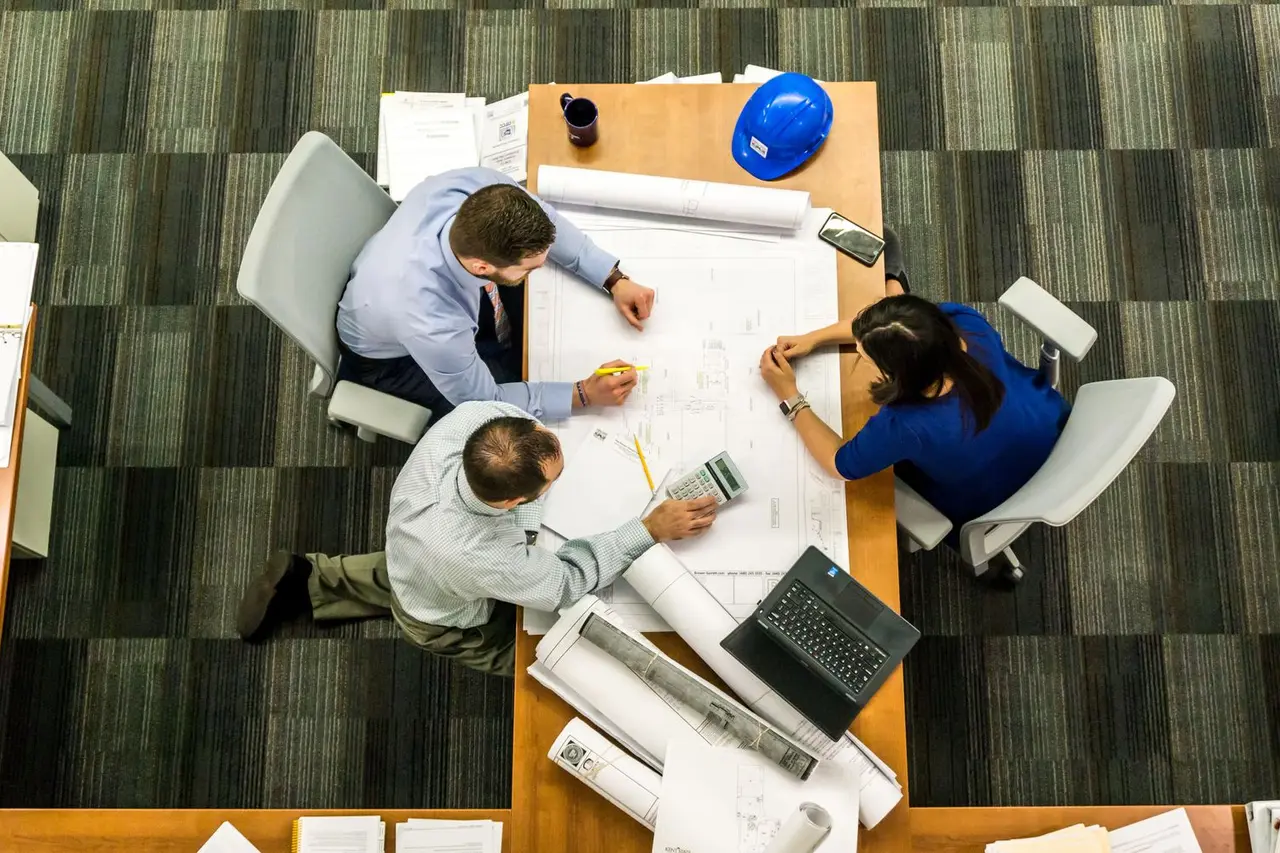 Project team organizing plans and digital records around a table