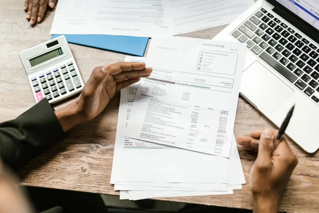 Business records, calculator, and laptop spread across a desk